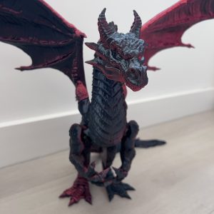 Подвижна фигура на дракон с ярко червени и черни цветове, вдъхновена от магическите същества като Тан и Аннар в Четвърто крило, с изразителни детайли и реалистични движения.
